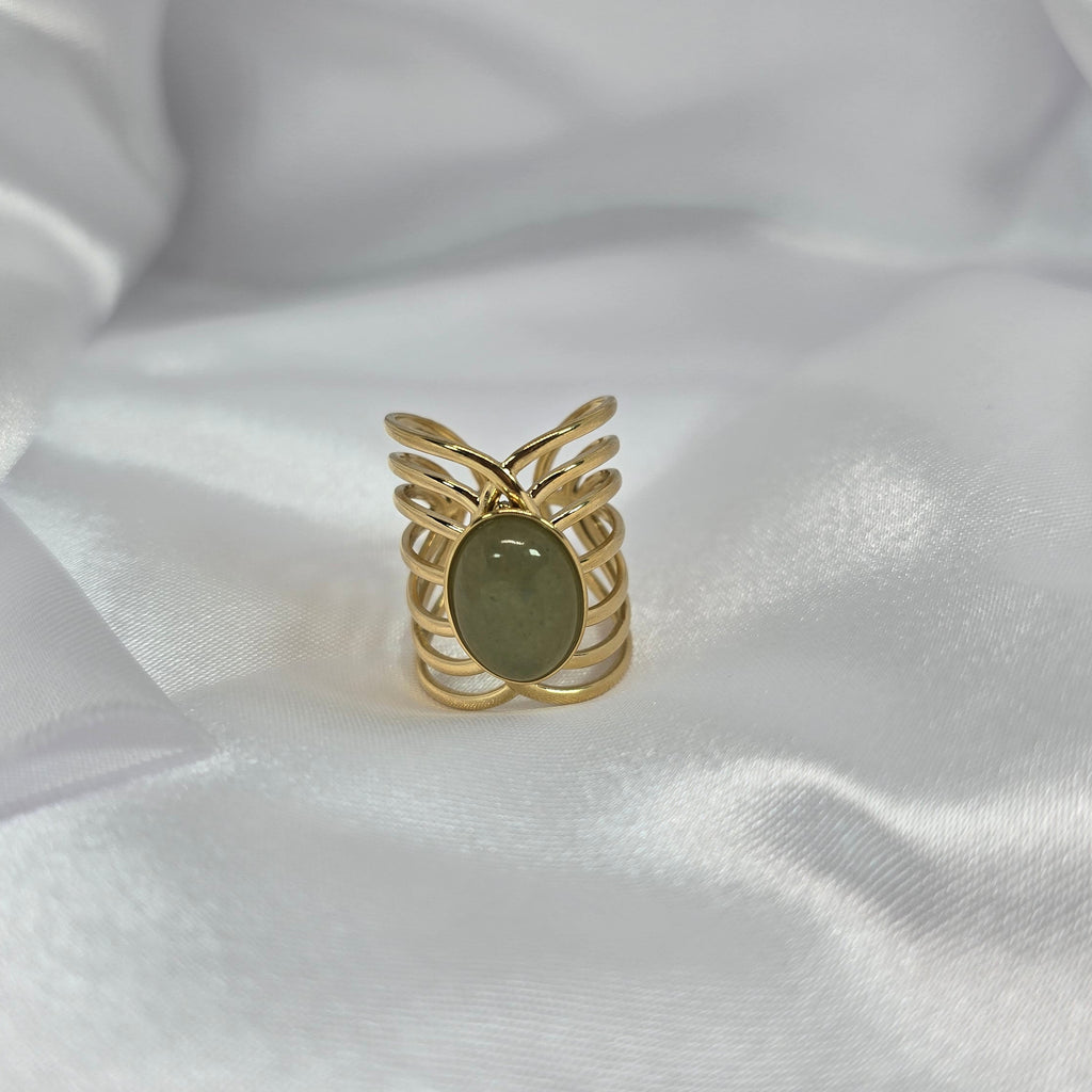 Gold ring with a green stone on a white fabric background