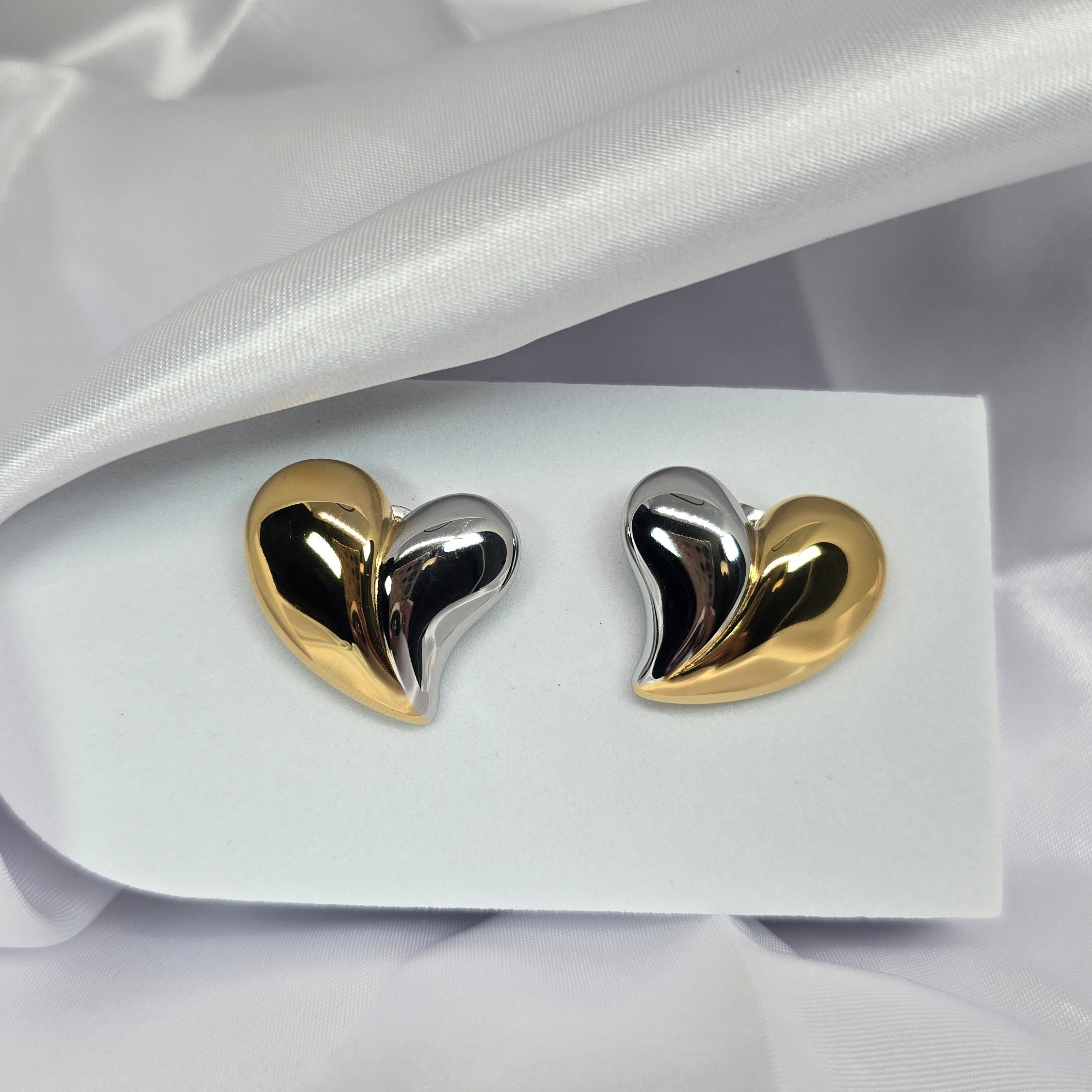 Heart-shaped earrings on a white card with a white fabric background