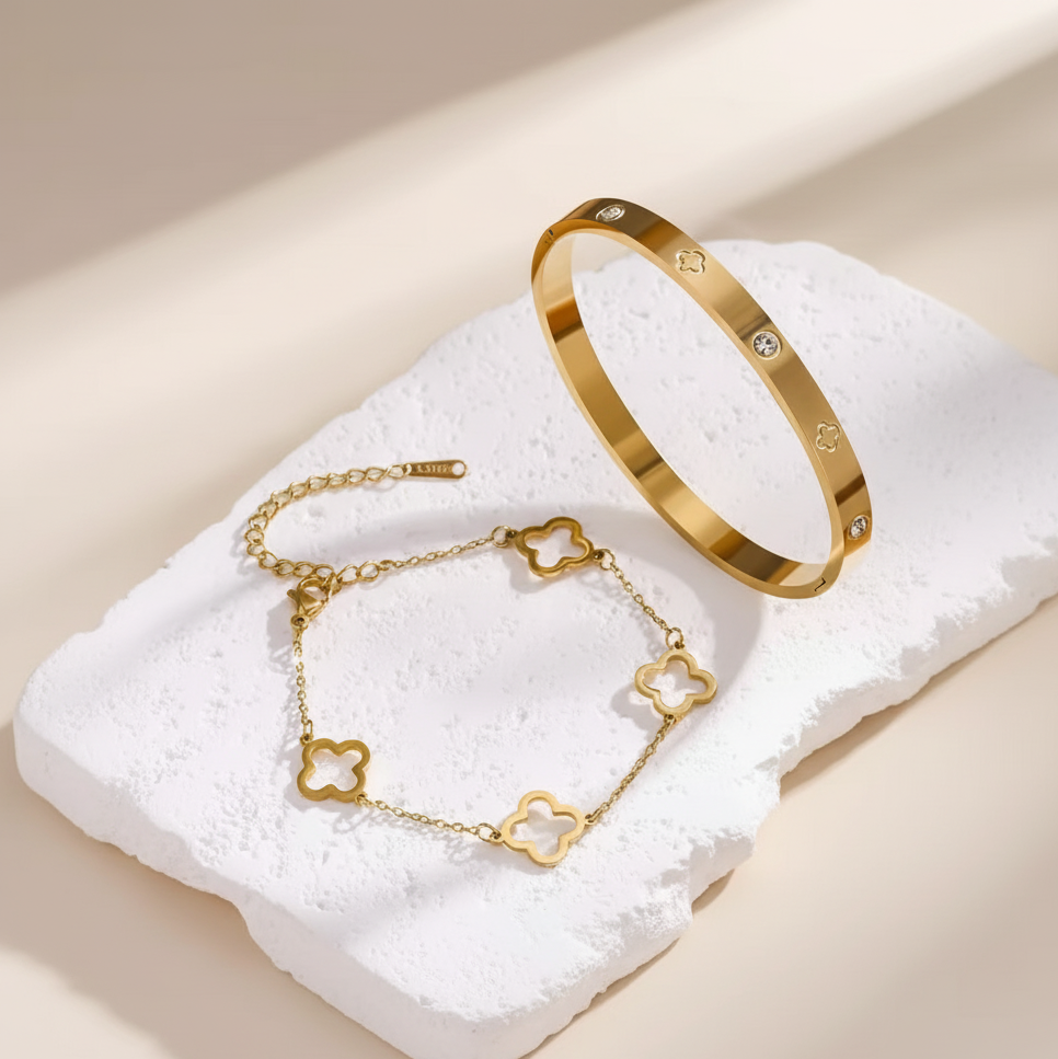 Gold bracelet and anklets on a white textured surface