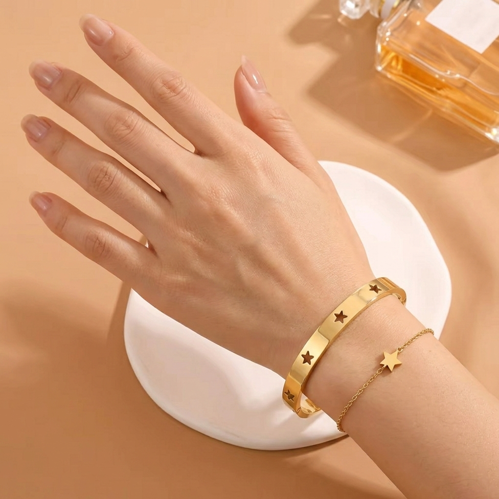 Hand wearing a gold bracelet on a beige background