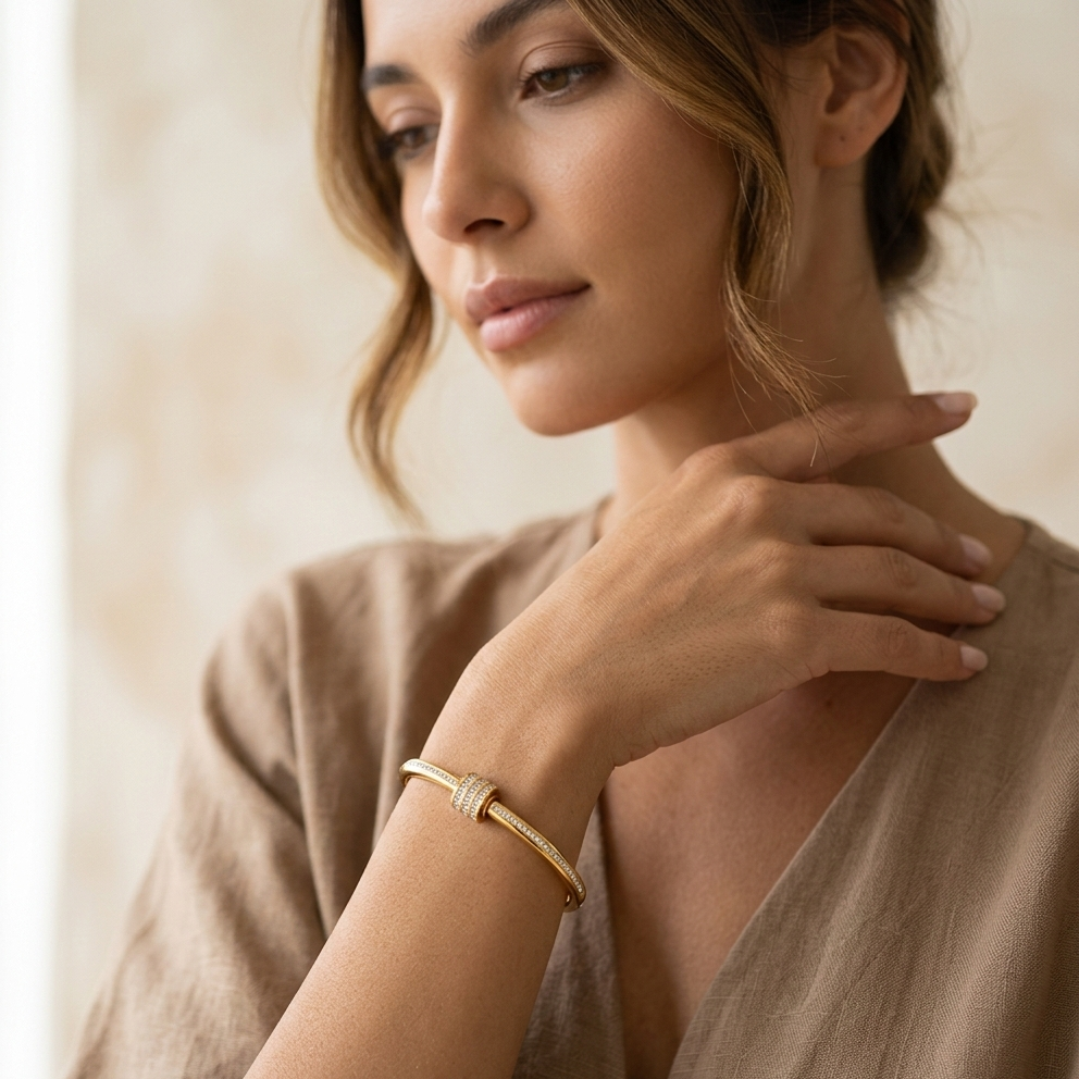 Woman wearing a gold bracelet on a neutral background