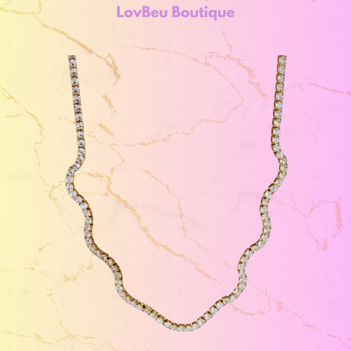 A wavy, scalloped necklace paved with clear rhinestones, displayed on a pastel pink and yellow marble-textured background with the text 'LovBeu Boutique' at the top.