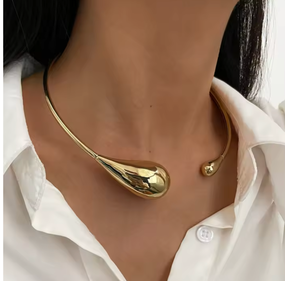Gold necklace worn by a person with a white shirt