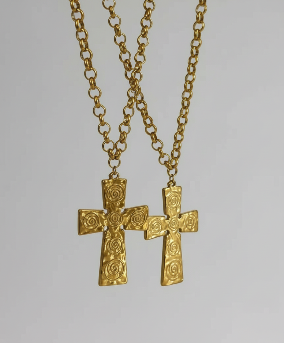 Gold cross necklace with intricate designs on a blurred background