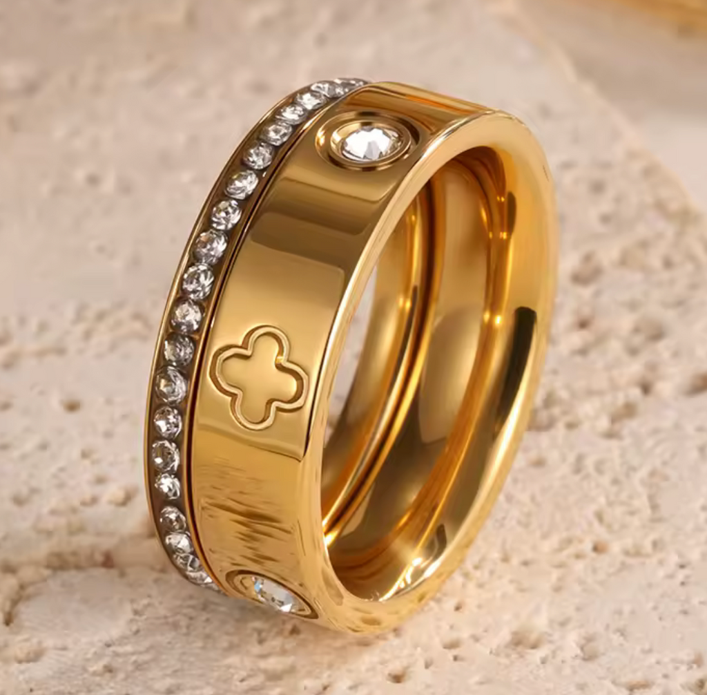 Gold ring with diamond accents on a textured beige surface