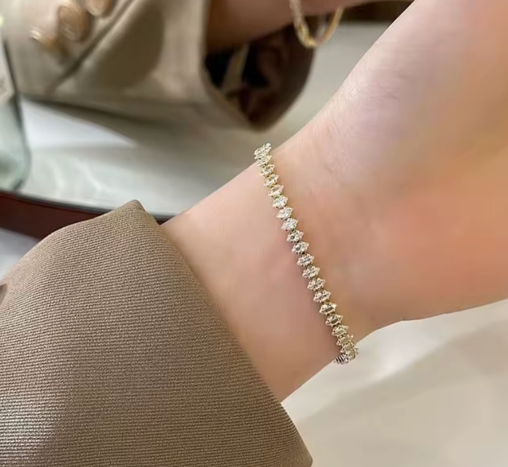 Close-up of a hand wearing a delicate bracelet on a neutral background