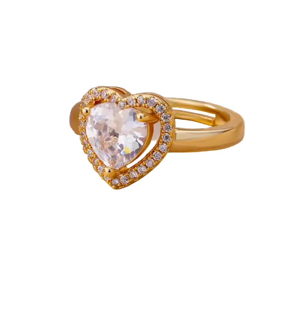 Gold heart-shaped ring with a clear gemstone on a beige background
