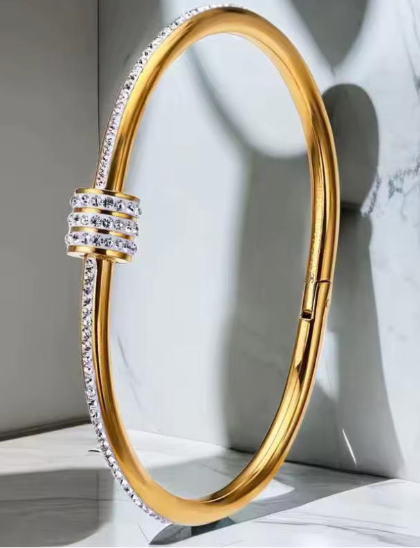 Gold bracelet with clear stones on a light gray background