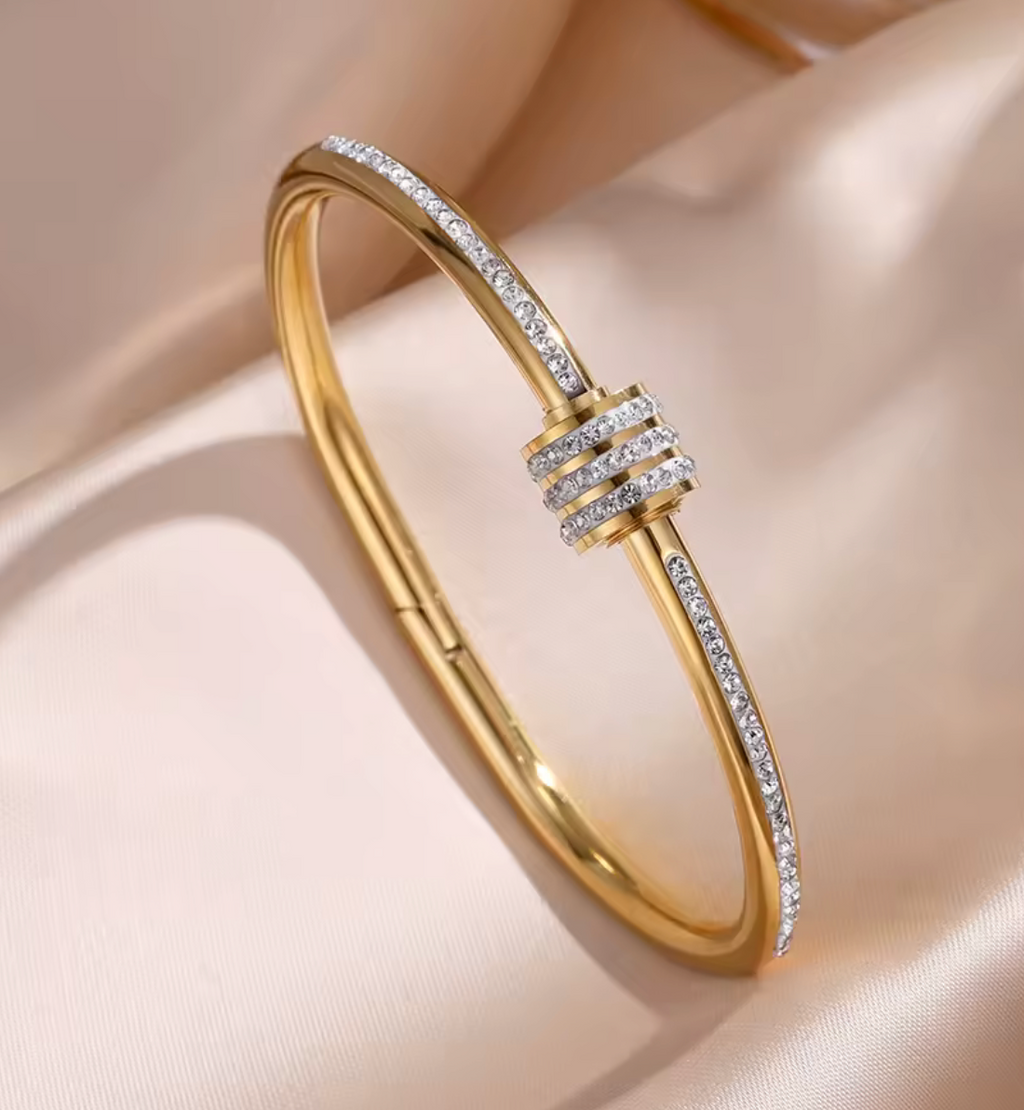 Gold bracelet with diamond accents on a beige background