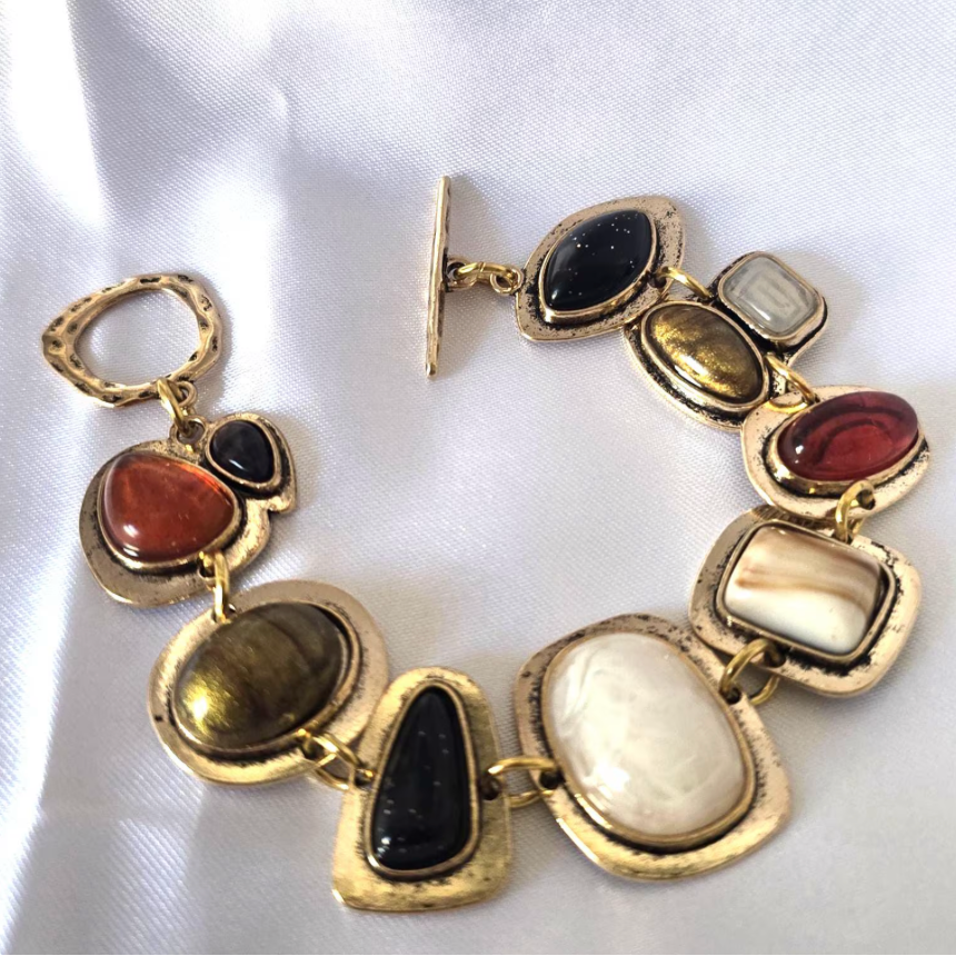 Gold bracelet with multicolored stones on a white background