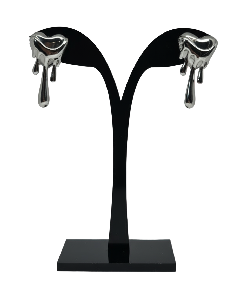 Black earring stand with silver earrings on a white satin background