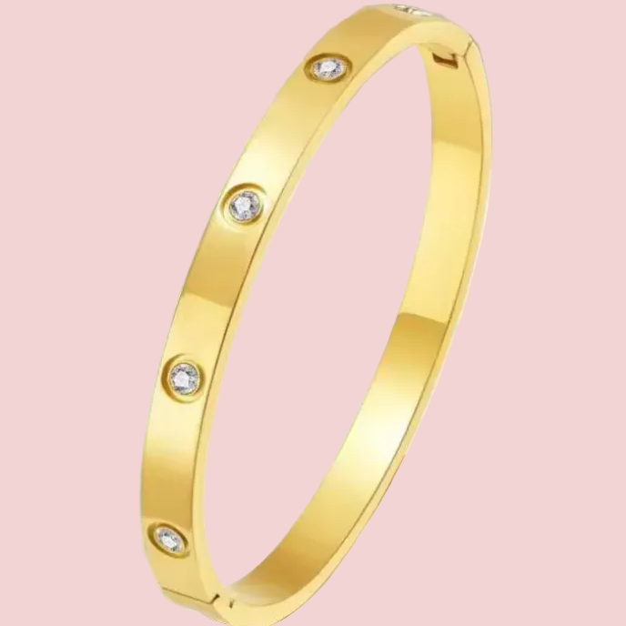 Gold bracelet with embedded diamonds on a pink background